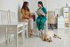Dierenarts in gesprek met een huisdiereigenaar in de dierenkliniek, met een hond op de vloer